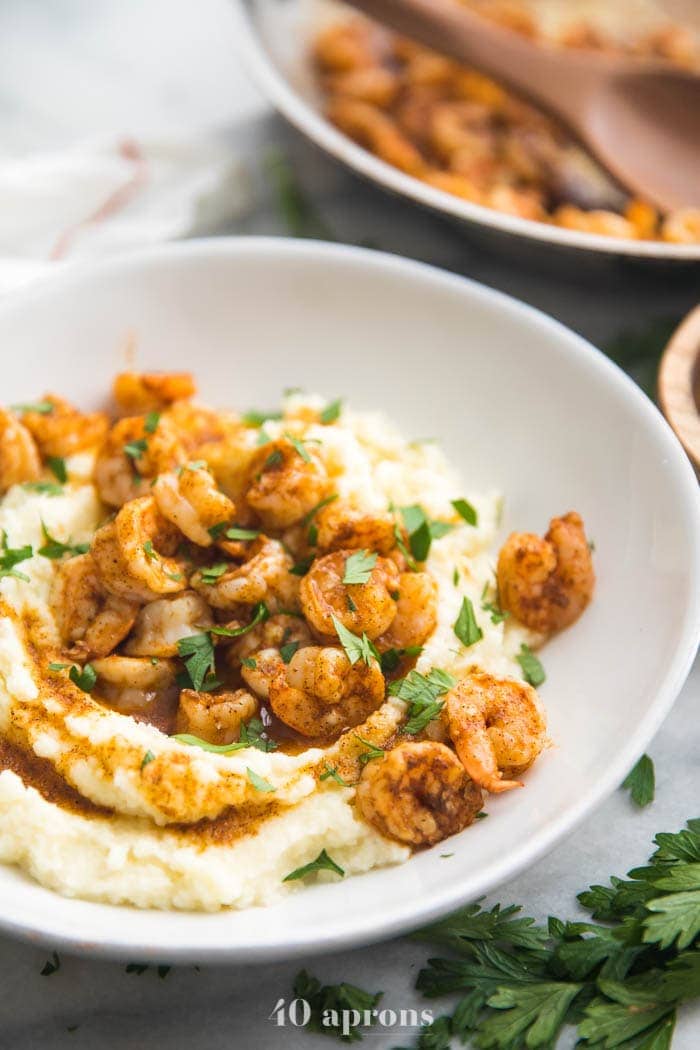 Whole30 healthy shrimp and grits in a bowl with skillet in background