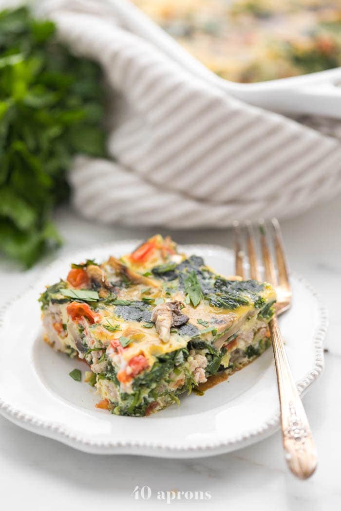Slice of Whole30 breakfast casserole with sausage on a plate with casserole in background
