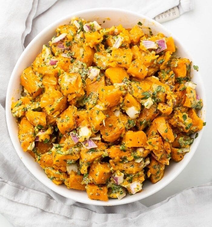 Sweet potato salad in a white bowl on a marble countertop