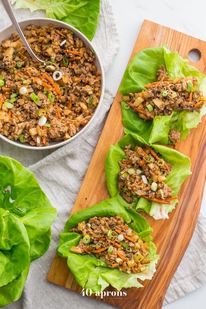 Healthy PF Changs lettuce wraps recipe on a board with a bowl of filling to the side