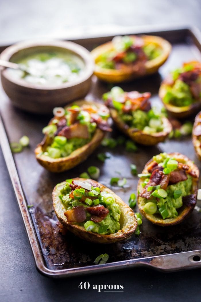 Paleo potato skins on a cookie sheet and topped with guacamole and bacon