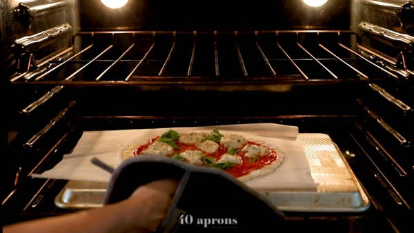 Slide pizza on parchment onto preheated overturned baking sheet