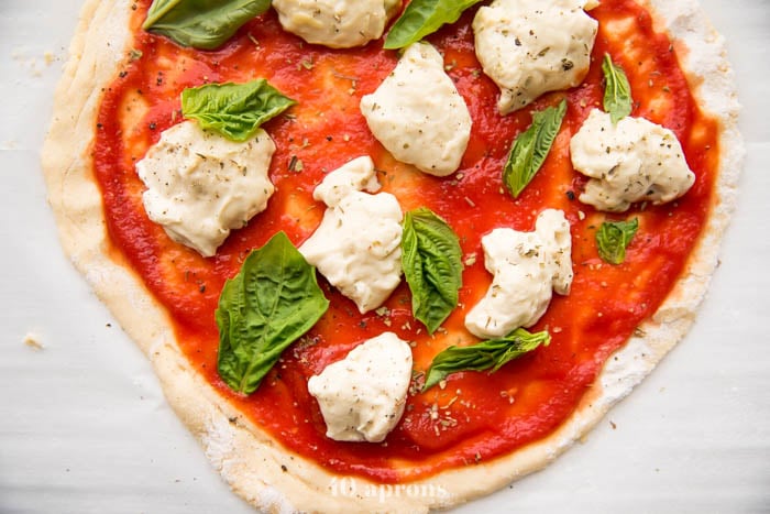 Paleo pizza crust with dairy free mozzarella and basil leaves