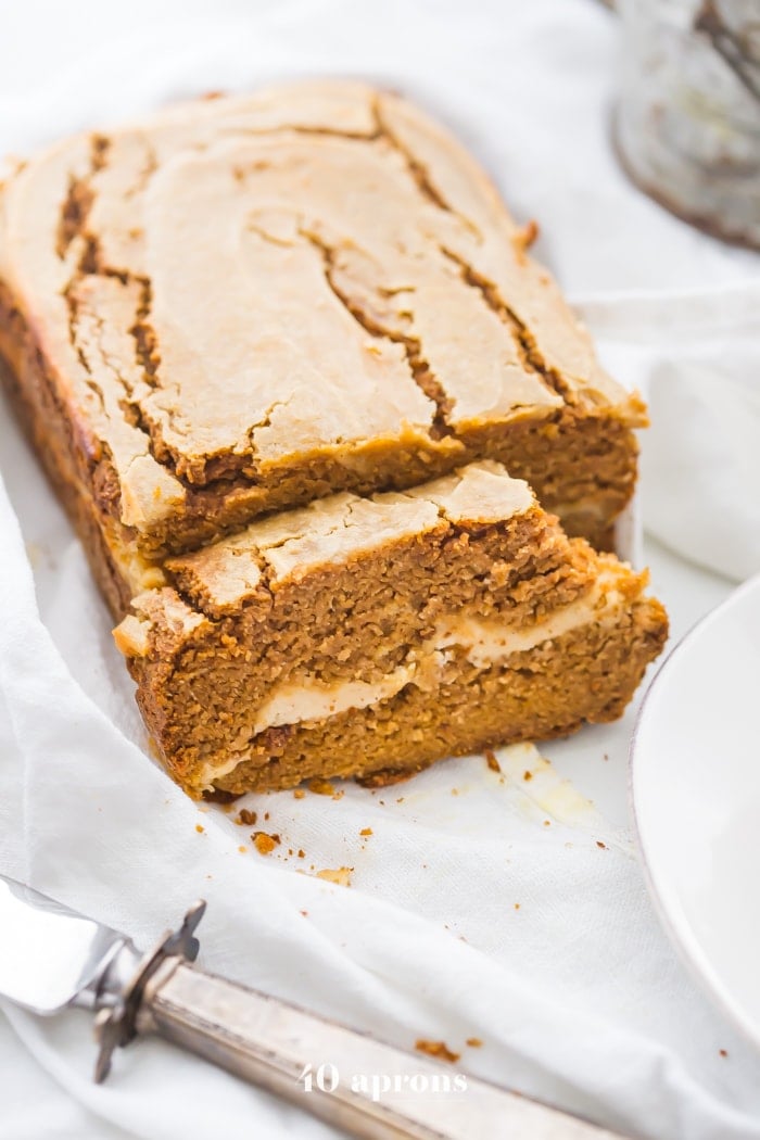 Paleo pumpkin bread with cream cheese swirl sliced with a bite out of one piece