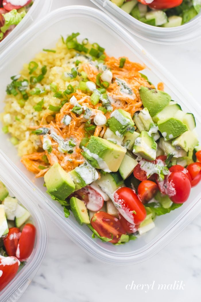 Buffalo chicken Whole30 meal prep recipe with avocado, cauliflower rice, and ranch dressing in container
