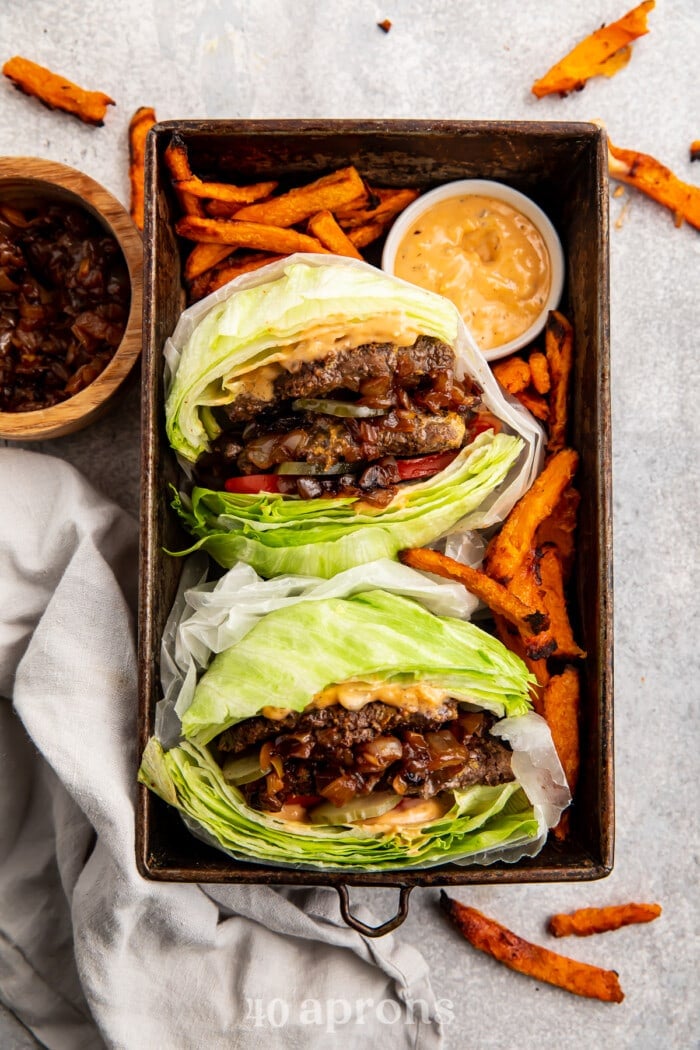 Overhaed view of two Whole30 In-n-out burgers in a serving tray with sweet potato fries and animal sauce