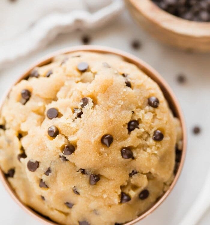Healthy cookie dough in a copper bowl with a bowl of chocolate chips in the corner