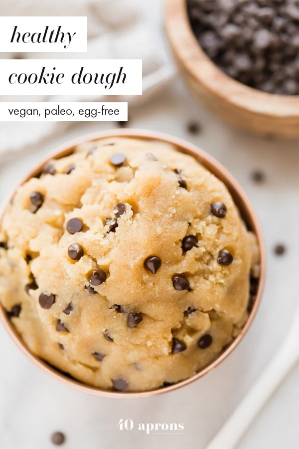 Healthy cookie dough in a copper bowl with a bite taken out and a bowl of chocolate chips in the corner