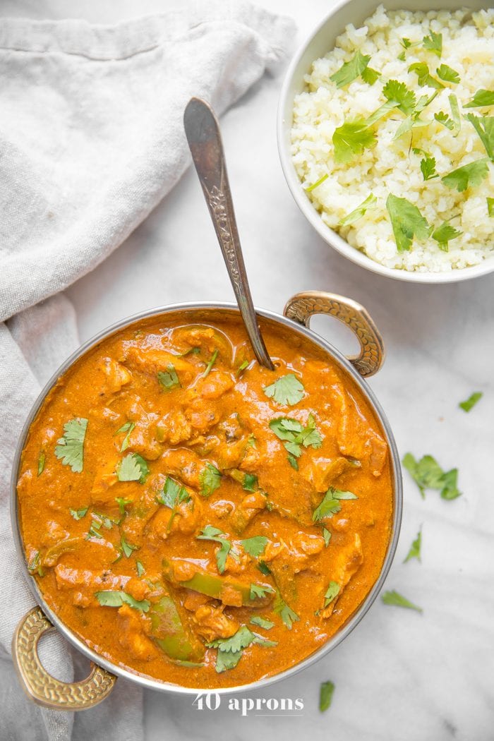 Instant Pot chicken tikka masala in a copper serving bowl with chopped cilantro and cauliflower rice