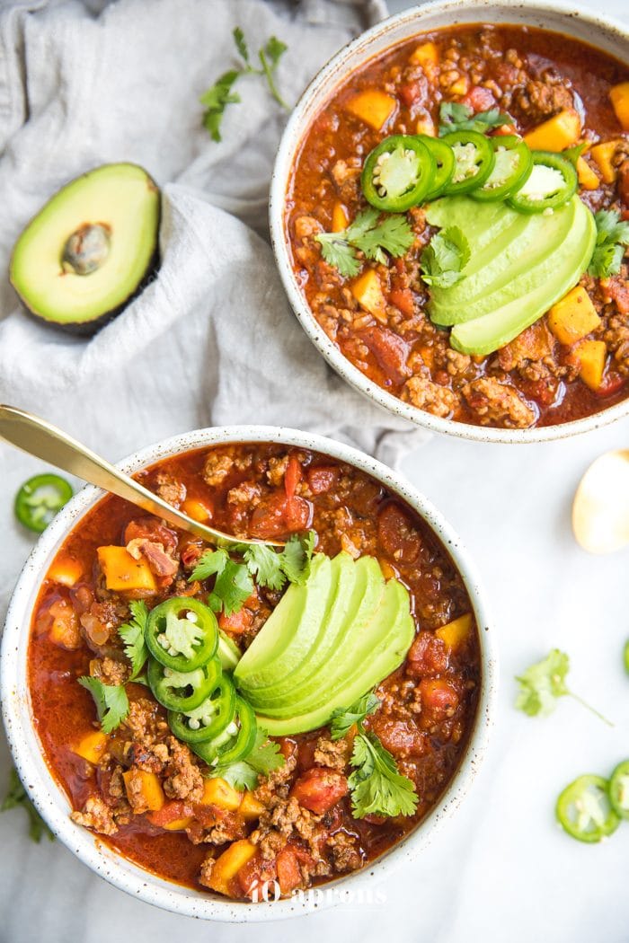 Two bowls of Instant Pot Whole30 chili with butternut squash topped with jalapenos and avocados