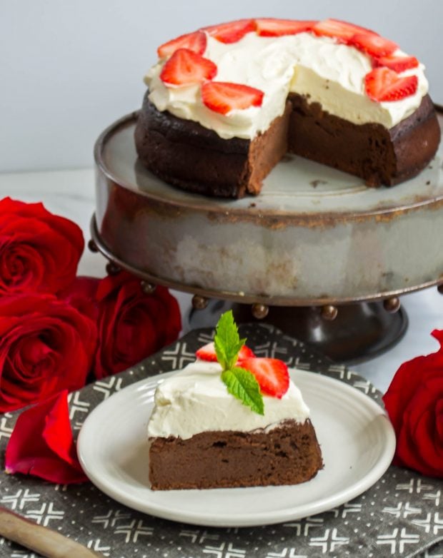 keto flourless chocolate cake on a cake stand with one slice cut