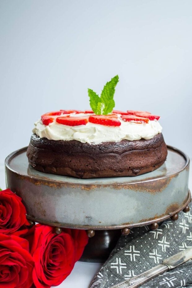 Flourless Keto Chocolate Torte Dessert topped with whipped cream on a cake stand 