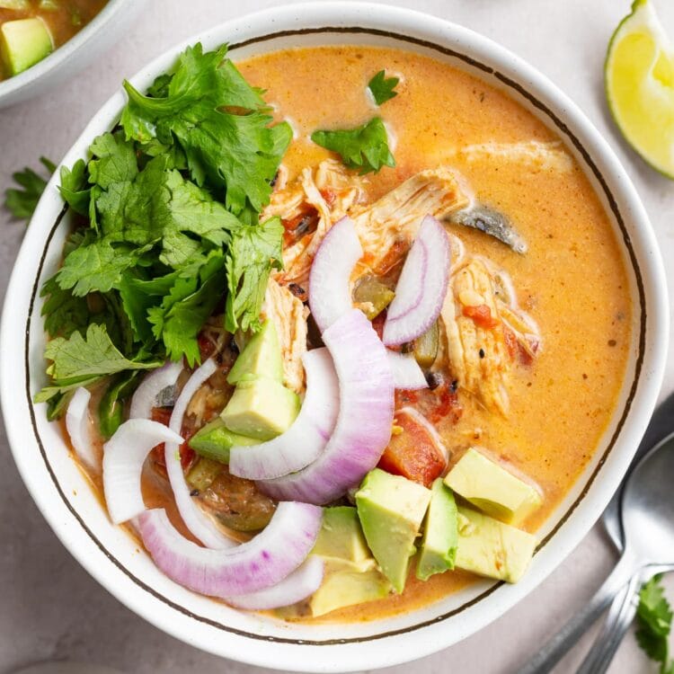 overhead image of whole30 instant pot chicken tortilla-less soup in a bowl with fresh cilantro, avocado, and red onion on top