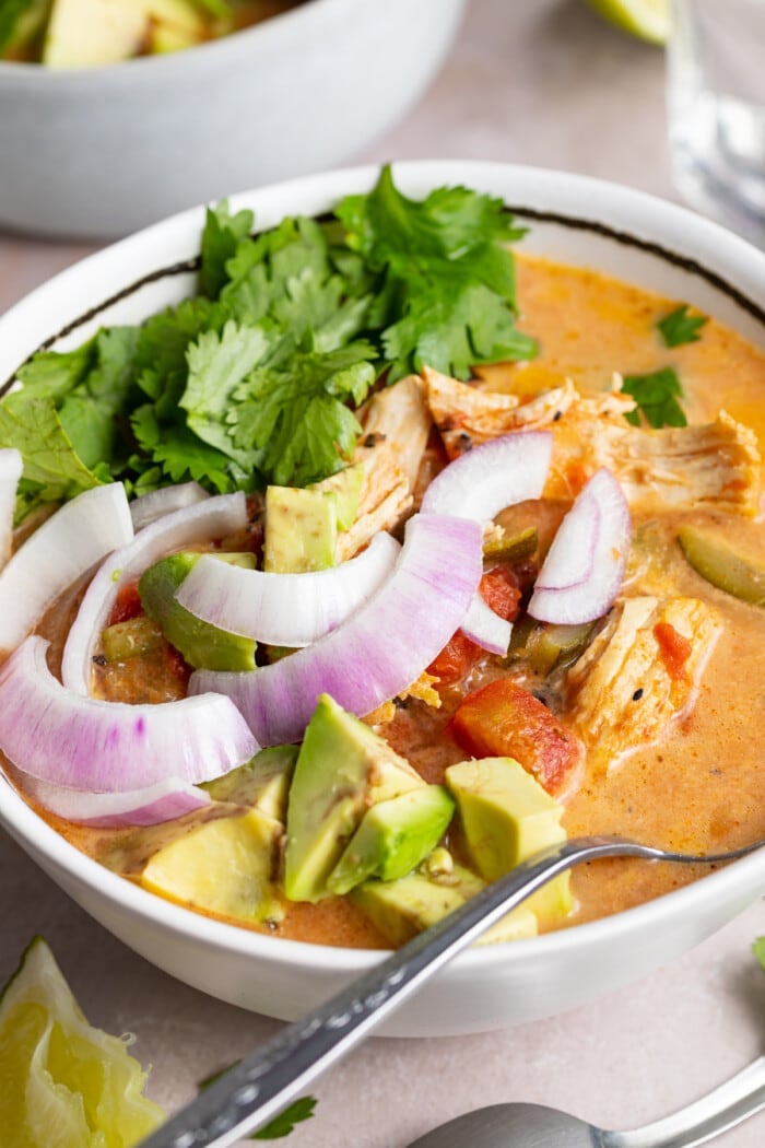 close-up image of whole30 instant pot chicken tortilla-less soup in a bowl with a glass of water and limes on the side