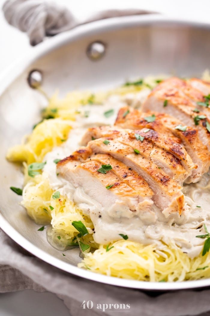 Healthy Whole30 chicken alfredo with spaghetti squash in a skillet topped with parsley