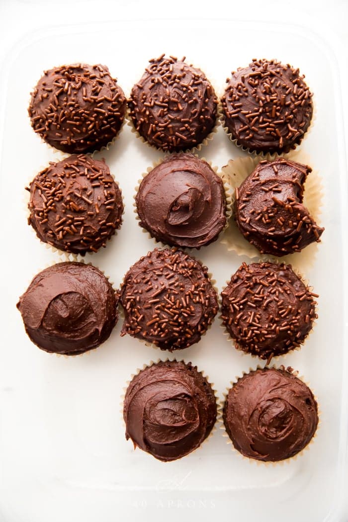 Overhead shot of many chocolate paleo cupcakes frosted with dark chocolate frosting and one bite taken out of one