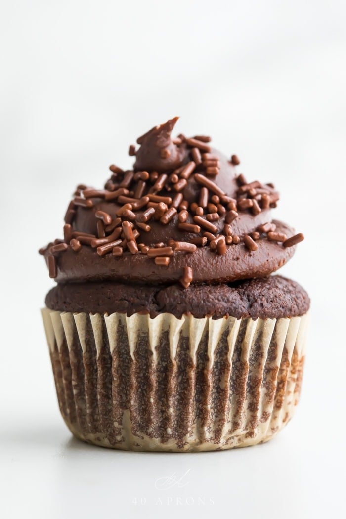 Frosted chocolate paleo cupcake with dark chocolate frosting in a swirl topped with chocolate jimmies