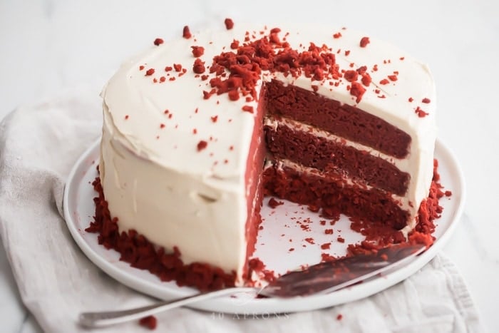 Three layer gluten free red velvet cake with paleo cream cheese frosting sliced open 