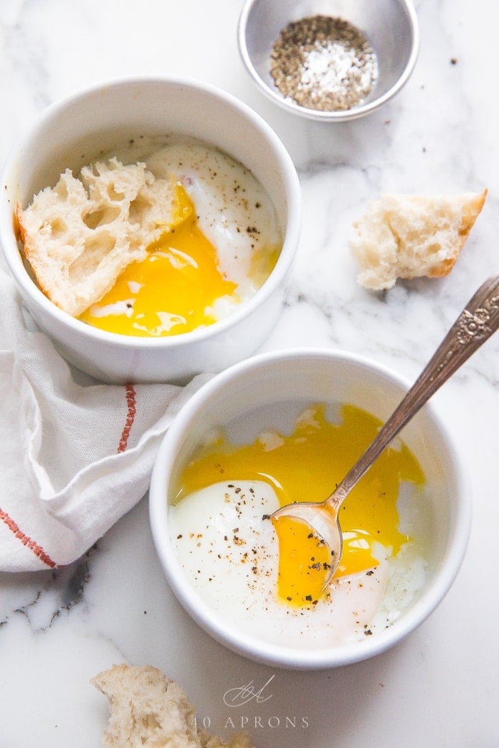 Two bowls with sous vide eggs topped with pepper and hunks of bread