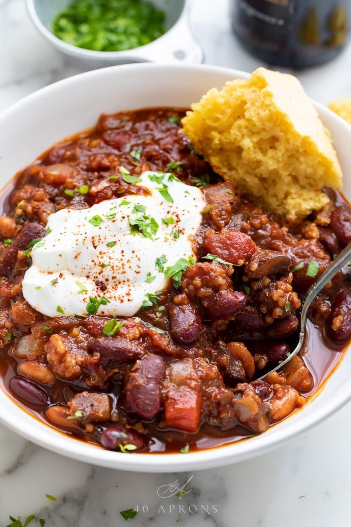 Chili served in a bowl with a spoon and piece of cornbread