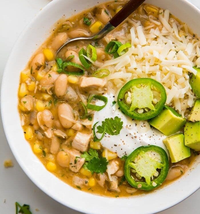 white bean chili in a white bowl with fresh toppings