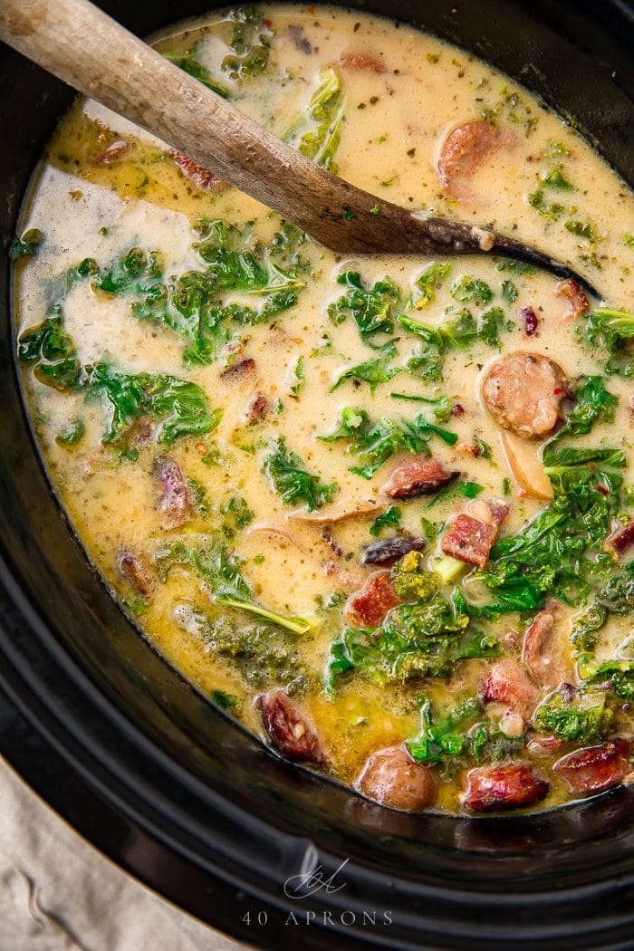 A spoon stirring the zuppa toscana in the crockpot