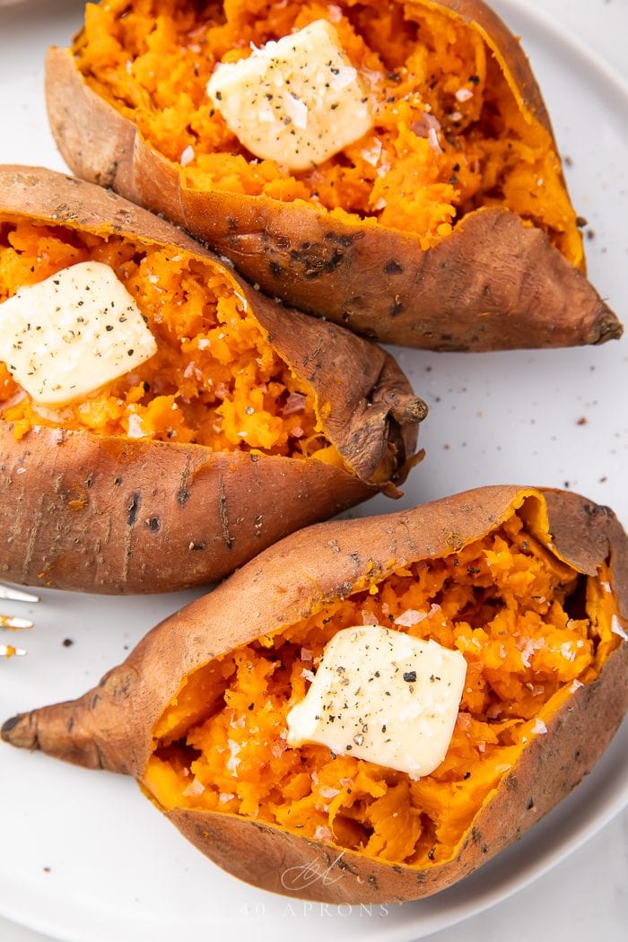 Three cooked sweet potatoes on a white plate