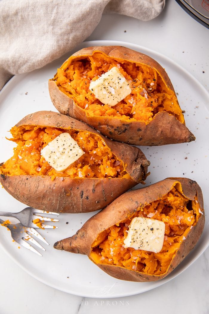 Three sweet potatoes on a plate with butter