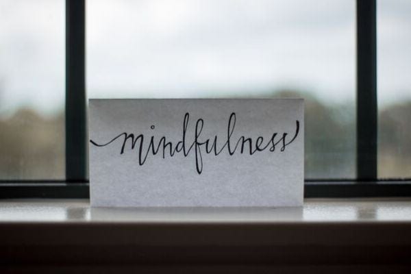 a small piece of paper with the word mindfulness written on it leaning against a window 