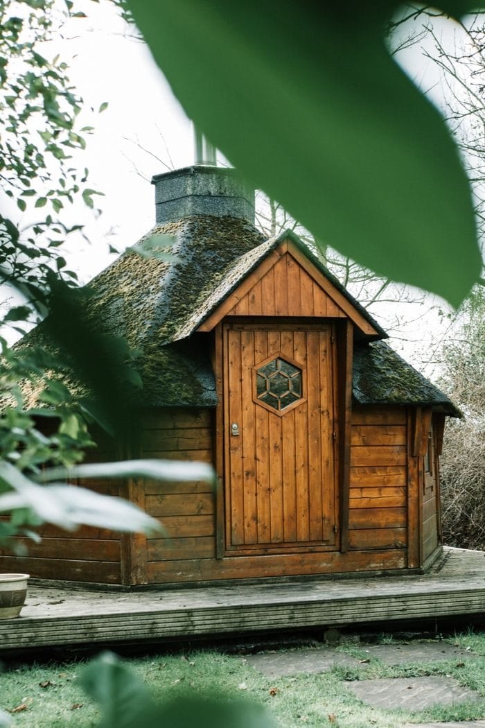 a small wooden Finnish sauna cabin in an autumnal garden 