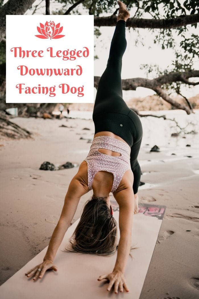 a woman  holding the yoga position three legged downward facing dog on a beach