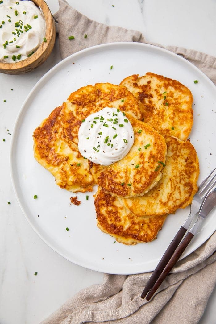 Leftover mashed potato pancakes on a white plate with a knife and fork