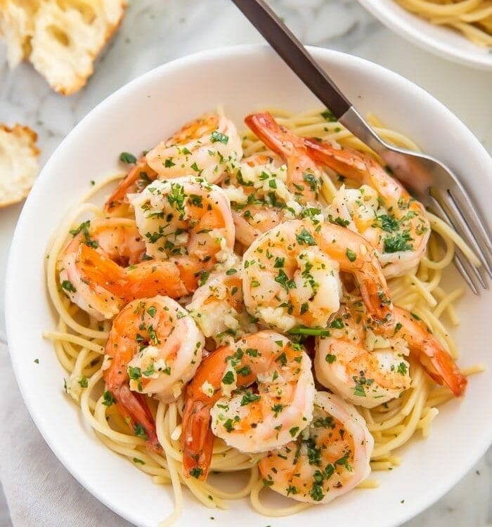 Garlic butter shrimp served with pasta in a white bowl