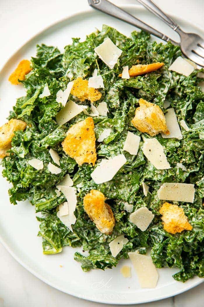Kale caesar salad on a white plate with croutons