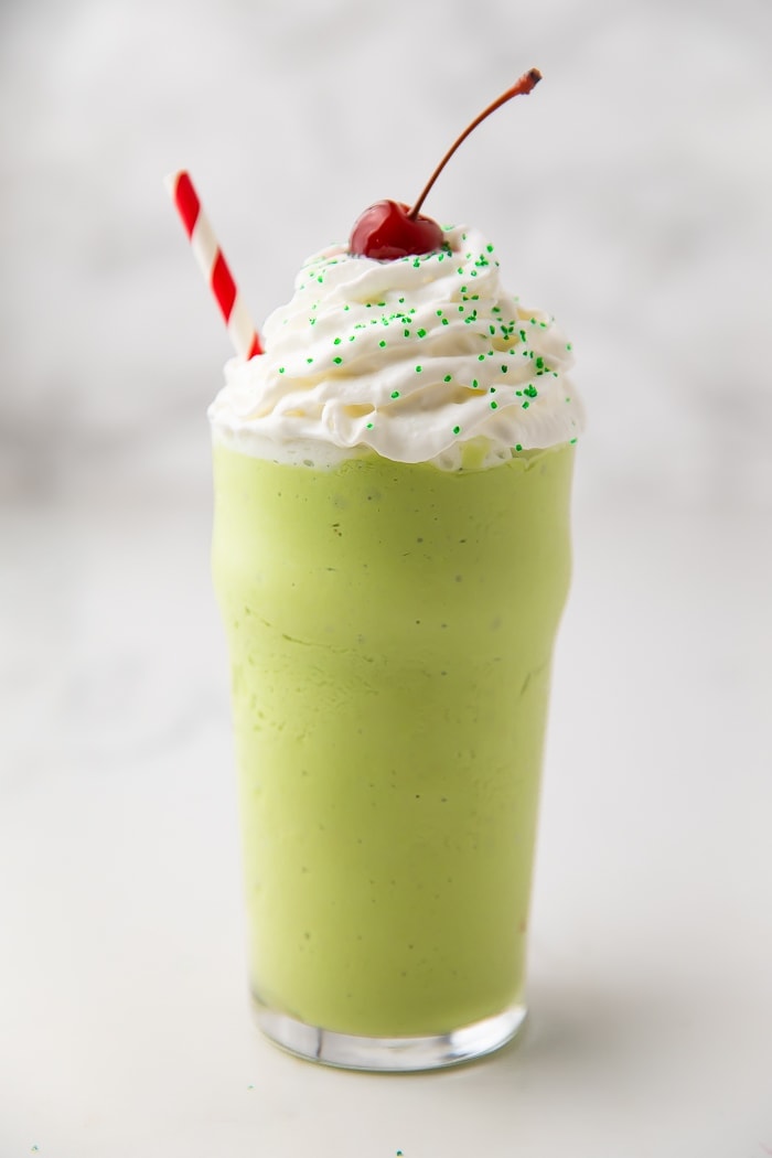 Healthy mint shake in a glass with whipped cream and a cherry
