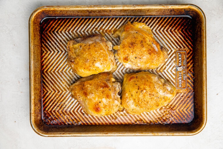 Cooked chicken thighs on a baking sheet