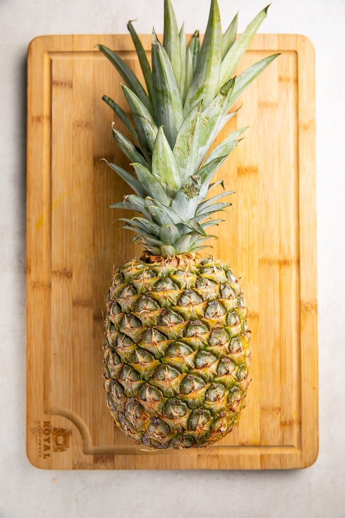 A whole pineapple lying on a cutting board