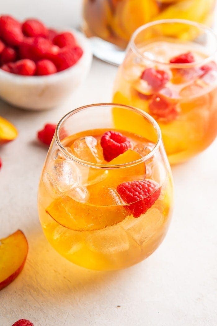 White wine sangria with peaches and raspberries in a glass