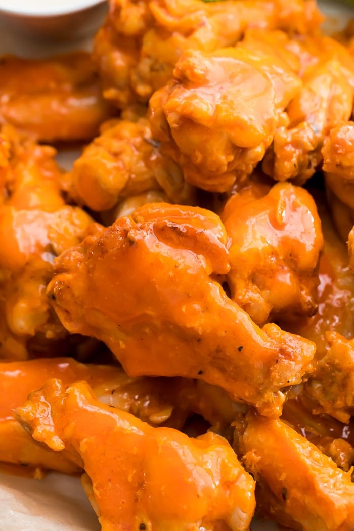 close-up of a pile of fried chicken wings smothered in buffalo sauce