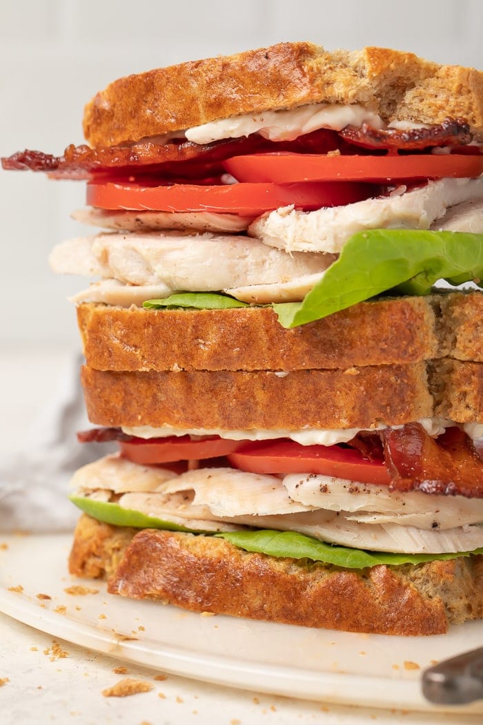 Turkey, lettuce, bacon, and tomato sandwiches made from paleo bread stacked on top of each other