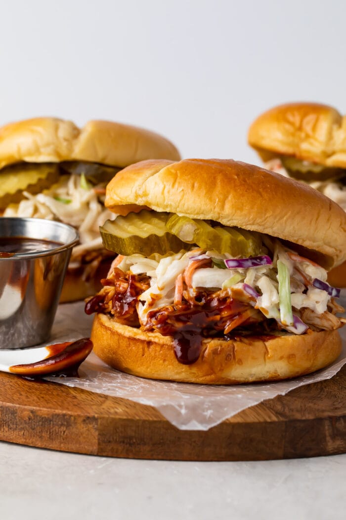 Three Instant Pot BBQ chicken sandwiches wit coleslaw and pickles