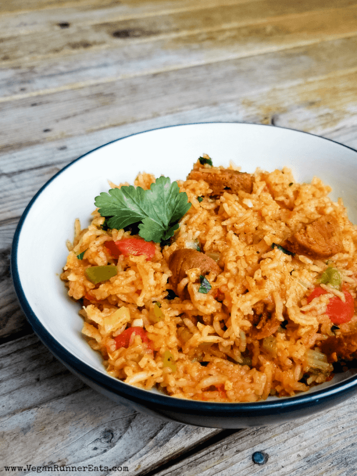 Vegetarian jambalaya in a dark bowl with white interior on a wooden table