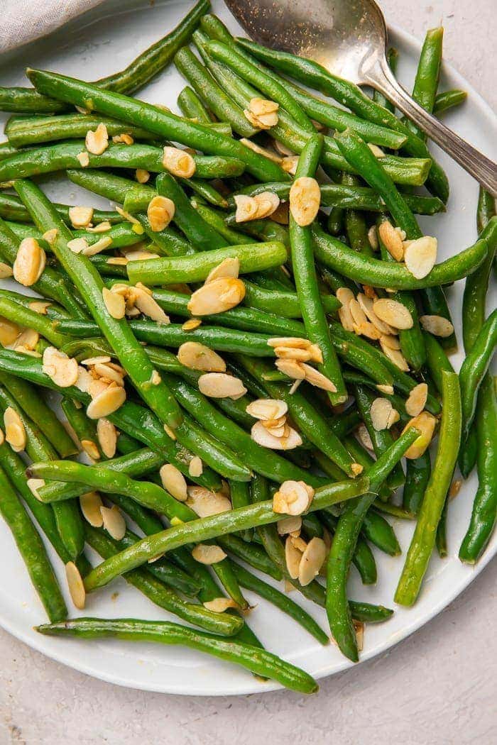 Green beans with almonds on a white platter