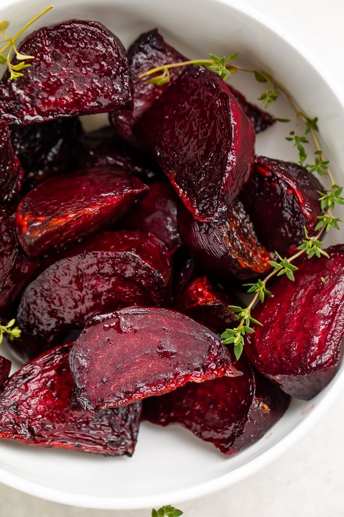 Deep red beets with green garnish in a white bowl