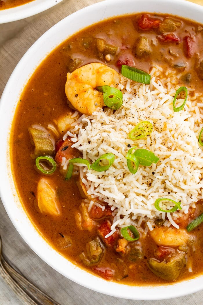 Shrimp gumbo with steamed rice and green onions in a white serving bowl
