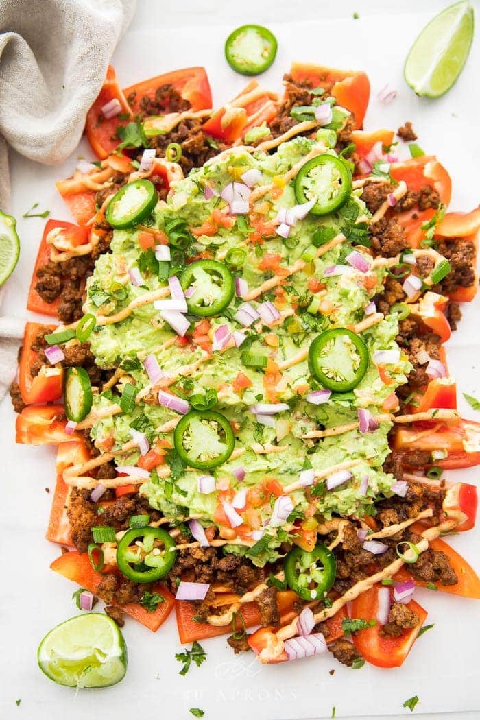 A giant platter of bell peppers, ground beef, guacamole, and other nacho toppings