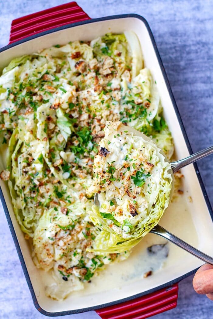 A spoonful of cabbage above a Corningware dish of cabbage in a creamy cheese sauce