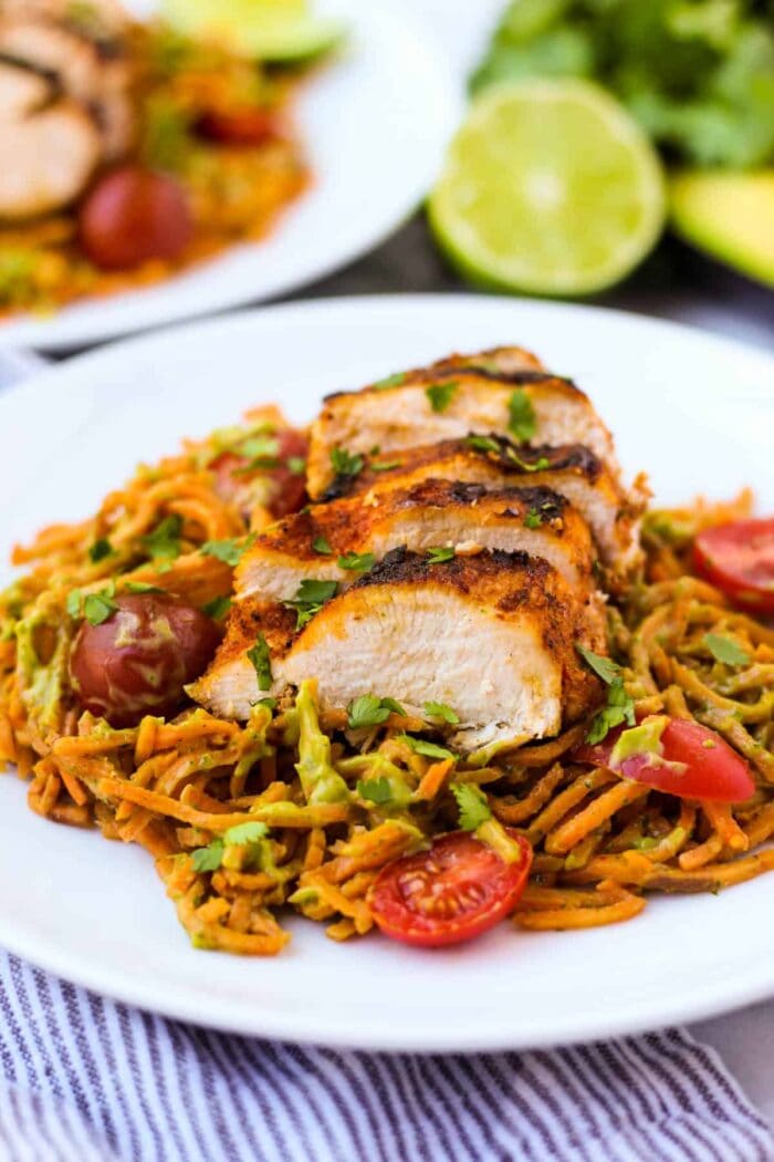 Whole30 chili dusted chicken with sweet potato noodles and avocado sauce on a white plate