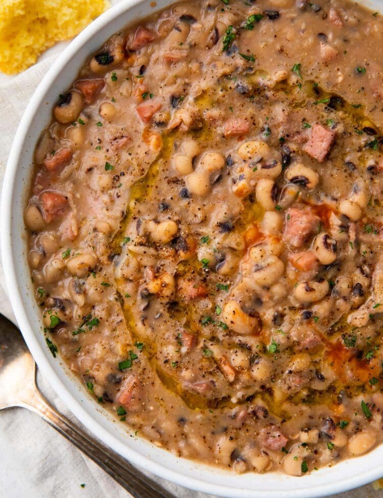 White bowl holding instant pot black eyed peas with ham, bacon, and onion
