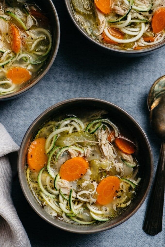 Whole30 chicken zoodle soup in a black bowl